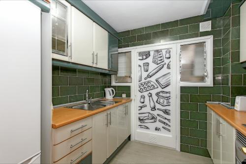 une cuisine avec un mur recouvert de dessins d'appareils dans l'établissement Apartment Arena - Lloret de Mar, à Lloret de Mar