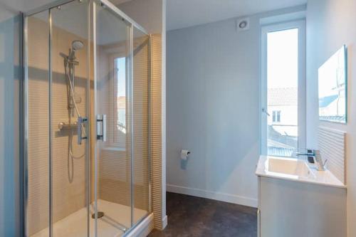 a bathroom with a glass shower and a sink at Le Balbec in Cabourg