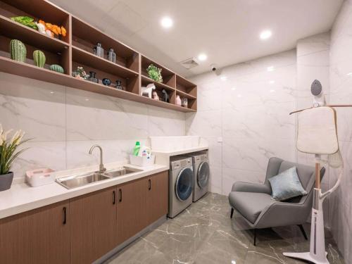 a kitchen with a sink and a washing machine at Magnotel Business Jinan Zoo Wuyingshan North Road Flagship Hotel in Beiyuan
