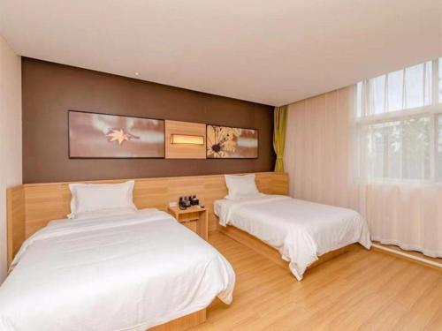 two beds in a room with white sheets at IU Hotel Binzhou University in Binzhou