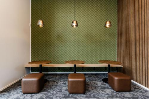 two tables and two stools in a room with green wallpaper at Haka House Rotorua in Rotorua