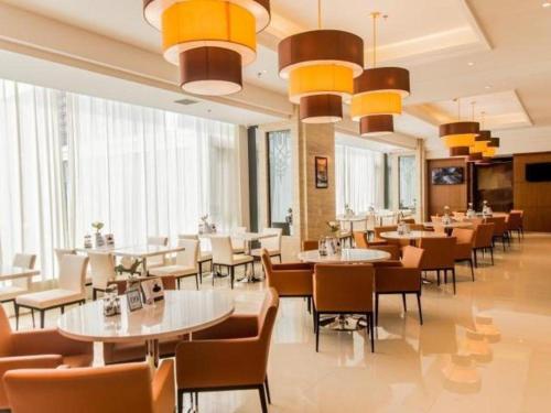- un restaurant avec des tables, des chaises et de grandes fenêtres dans l'établissement Jinjiang Inn Select Hohhot Chengjisihan Square Metro Station, à Hohhot