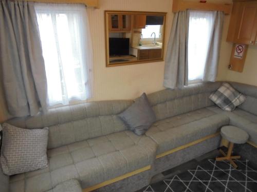 a couch in a living room with two windows at 6 berth 3 bedroom Northshore Skegness FREE WIFI in Skegness