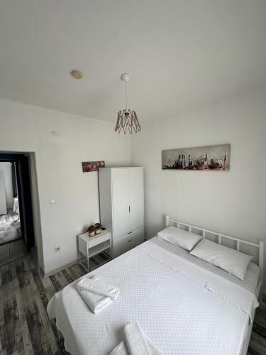 a white bedroom with a white bed and a chandelier at Denizati Pension in Bodrum City