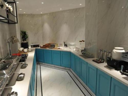a kitchen with blue cabinets and a white counter top at Magnotel Jining Canal City Shop in Jining
