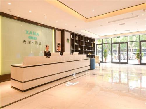 a woman standing at a reception desk in a lobby at Xana Lite·Kaifeng Small Song City Millennium City Park in Kaifeng