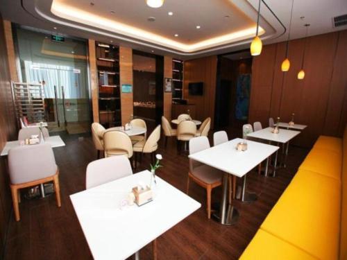 un restaurante con mesas y sillas blancas en una habitación en Jinjiang Inn Dalian Huanan Square Zhonghua Road en Nan-kuan-ling