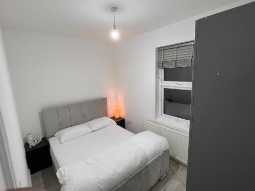 a white bedroom with a bed and a window at F4 Luxury Stays One bed apartment with Parking in Ilford