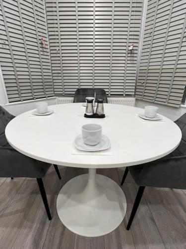 a white table with two cups and saucers on it at F4 Luxury Stays One bed apartment with Parking in Ilford