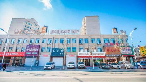 un gran edificio con coches estacionados frente a él en Jinjiang Inn Select Changchun Jiutai Minkang Road, 