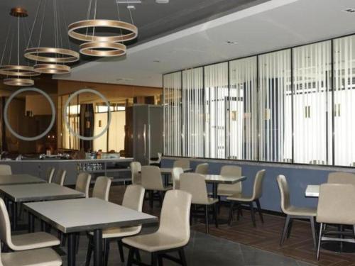 ein Esszimmer mit Tischen, Stühlen und Spiegeln in der Unterkunft Jinjiang Inn Select Jiuquan Wanda Plaza in Jiuquan