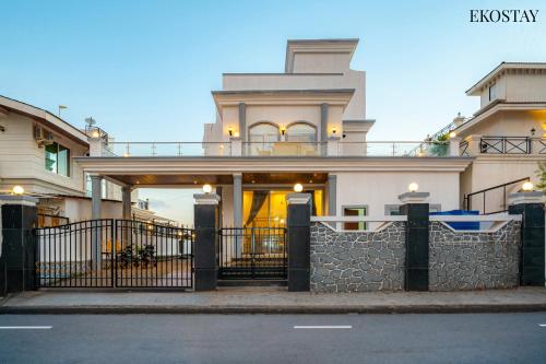 a large white house with a fence in front of it at Ekostay Cliffside Villa I Mountain View in Lonavala