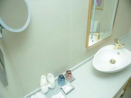 ein weißes Badezimmer mit einem Waschbecken und einem Spiegel in der Unterkunft Lavande Hotel Taizhou Medicine Market People's Square in Taizhou