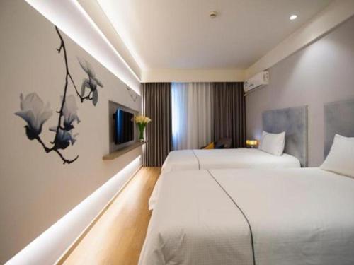 a hotel room with two beds and a painting on the wall at Magnotel Hotel Qionghai Wanquanhe Aihua Road in Qionghai