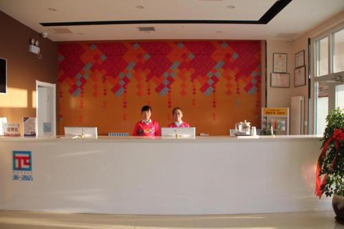 Dos mujeres sentadas en un mostrador en una tienda en PAI Hotel Hami Baoda Logistics Park Test Station en Hami