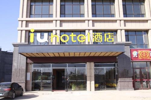 a hotel with a sign on the front of a building at IU Hotel Zhangye High-Speed Railway Station in Zhangye
