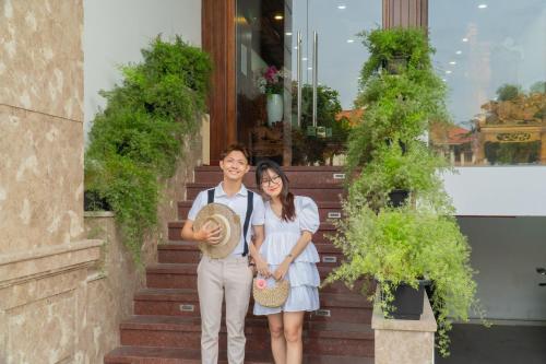 a man and woman standing in front of a building at SeaColor Beachstay Danang Hotel by Haviland in Da Nang