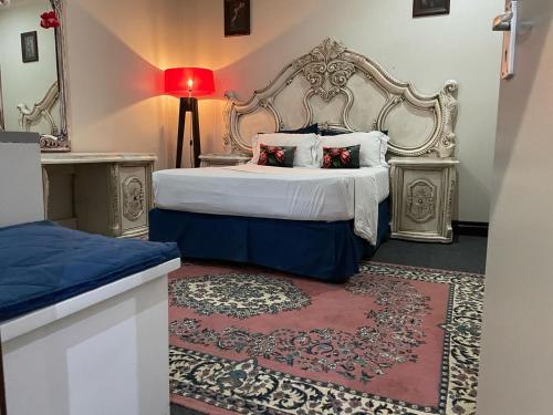 a bedroom with a large bed and a red lamp at Afrite Rooms Goodwood in Cape Town