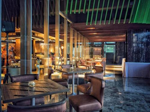 un restaurante con mesas de madera y sillas de cuero en Patra Cirebon Hotel & Convention en Tangkil