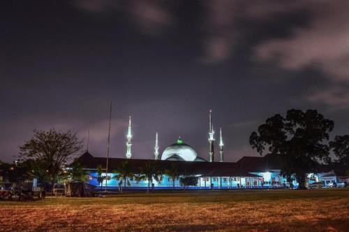 a mosque lit up at night with a field in front at KoolKost near Stasiun Poris Tangerang in Porisgaga