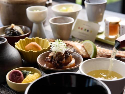 a table with bowls of food on a table at Yufuin Luxury Villa -zakuro- in Yufuin