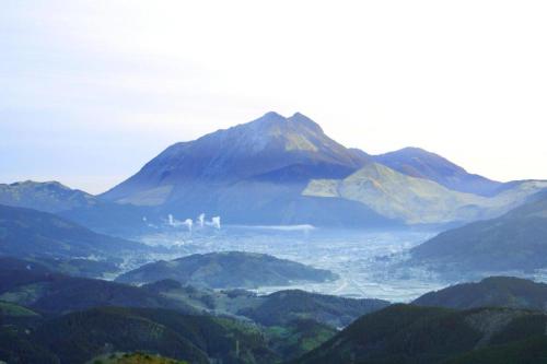 a view of a mountain with a city in the distance at Yufuin Luxury Villa -zakuro- in Yufuin
