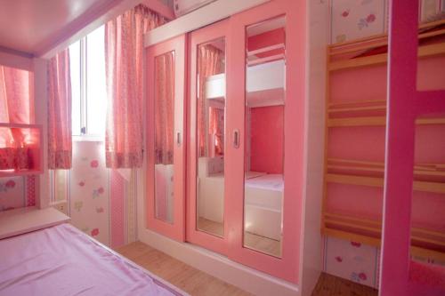 a pink room with a bed and some shelves at Kara's Condotels Cebu in Cebu City