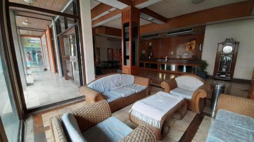 sala de estar con sofás, sillas y reloj en Samainiyom Hotel, en Sathani Phitsanulok