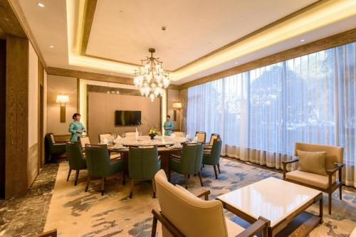 ein Esszimmer mit einem Tisch und Stühlen sowie einem großen Fenster in der Unterkunft Landison Xinan Hotel Hangzhou in Jiande