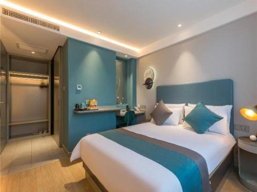 1 dormitorio con 1 cama grande y paredes azules en Magnotel Hotel Liaocheng Development Zone Zhenhua Shopping Center, en Liaocheng