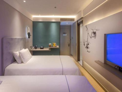 a bedroom with two beds and a flat screen tv at Magnotel Hotel Shiyan Wuyan Pedestrian Street in Shiyan