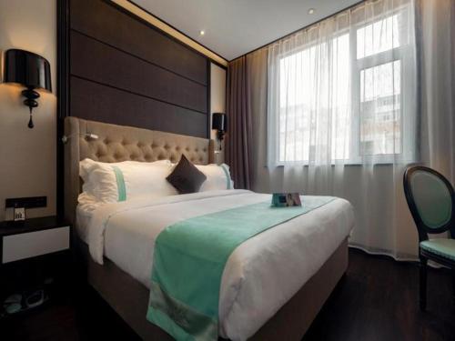 Cette chambre comprend un grand lit et une fenêtre. dans l'établissement Xana Hotelle·Lianyungang Donghai, à Donghai