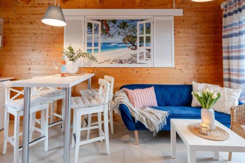 ein Wohnzimmer mit einem blauen Sofa, einem Tisch und Stühlen in der Unterkunft DOMKI LAURA z sauną i gorącą balią z jacuzzi in Jastrzębia Góra