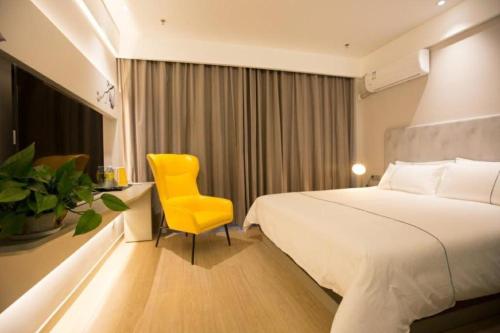 a hotel room with a bed and a yellow chair at Magnotel Hotel Rizhao Dengta Scenic Spot Lianyungang Road in Rizhao