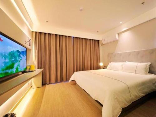 a hotel room with a bed and a flat screen tv at Magnotel Hotel Rizhao Dengta Scenic Spot Lianyungang Road in Rizhao
