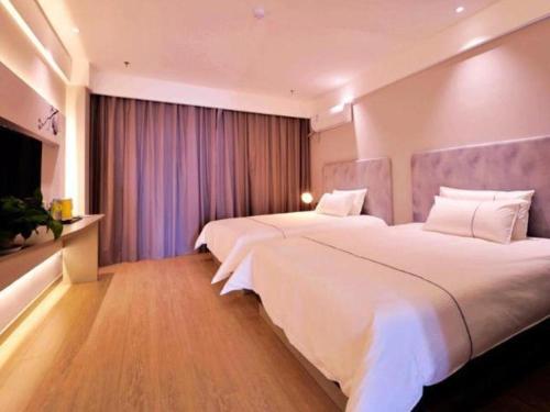 a hotel room with two beds and a television at Magnotel Hotel Rizhao Dengta Scenic Spot Lianyungang Road in Rizhao