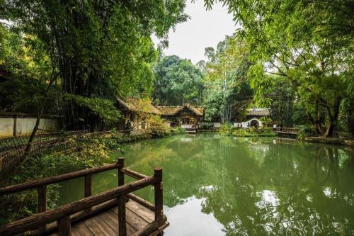 成都市にあるPAI Hotel·Chengdu Jinsha Museum Metro Stationの木製のベンチのある庭園の池