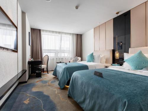 a hotel room with two beds and a television at Xana Deluxe Beijing Guang'anmen Metro Station in Beijing