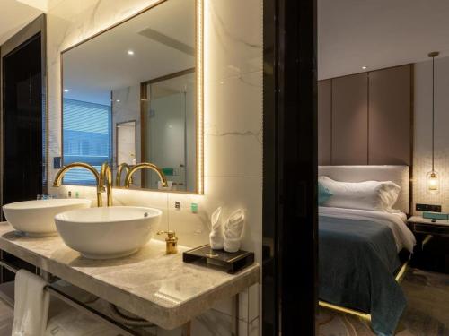 a bathroom with two sinks and a bed and a mirror at Xana Deluxe Beijing Guang'anmen Metro Station in Beijing