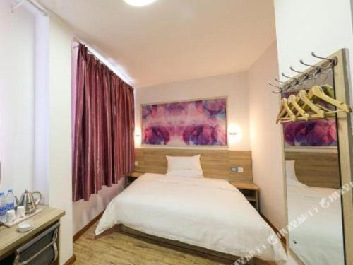 ein Schlafzimmer mit einem weißen Bett in einem Zimmer in der Unterkunft PAI Hotel·Hami Yingbin Avenue Airport in Hami