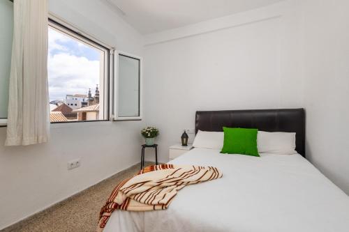 a bedroom with a bed with a green pillow and a window at Home San Jeronimo in Granada