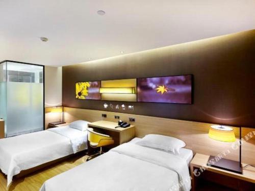 a hotel room with two beds and a tv on the wall at IU Hotel·Tianjin Binhai New District Yanghuo Market in Binhai