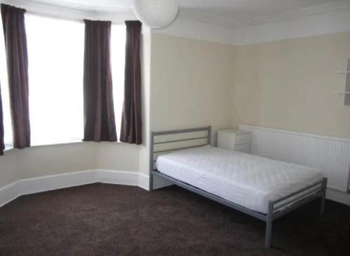 a white room with a bed and two windows at Durley house in Alphington