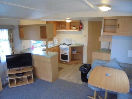 a small living room with a kitchen and a table at 8 Berth Northshore Skegness The Cottage Panel heated in Lincolnshire