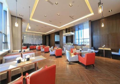 a lobby of a hotel with red chairs and tables at Echeng Hotel Dongying Kenli Destrict Government in Kenli