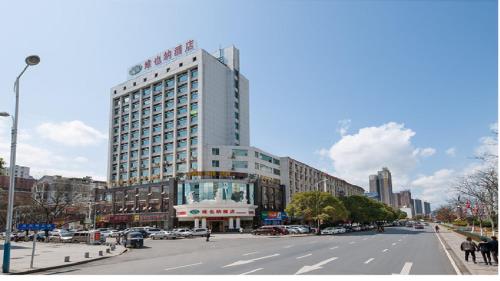 wysoki biały budynek na ulicy miejskiej z samochodami w obiekcie Vienna Hotel Jiangxi Jian Railway Station w Ji'an