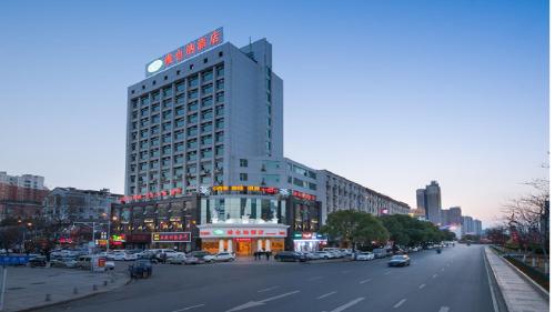 ein hohes Gebäude in einer Stadtstraße mit parkenden Autos in der Unterkunft Vienna Hotel Jiangxi Jian Railway Station in Ji'an