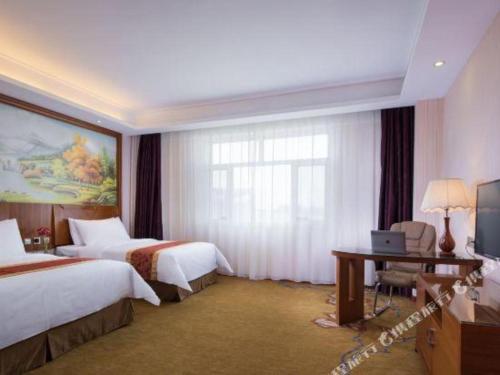 ein Hotelzimmer mit 2 Betten und einem Schreibtisch mit einem Laptop in der Unterkunft Vienna Hotel Tongliao Ke'erqin in Tongliao