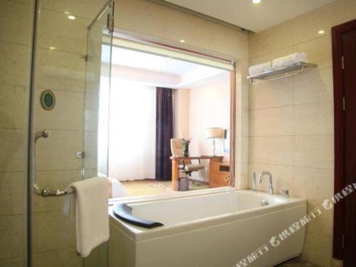 Vienna Hotel Tongliao Ke'erqin في تونغلياو: حمام مع حوض استحمام كبير في الغرفة