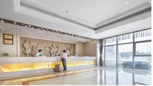 2 personnes debout au bar d'un bâtiment dans l'établissement Vienna Hotel Jiangsu Changzhou Zouqu Lamp Market, à Beigang